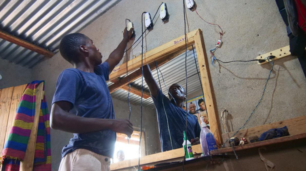Davie hangs back his clipper after shaving a customer. ©UNFPA/Malawi/2024.