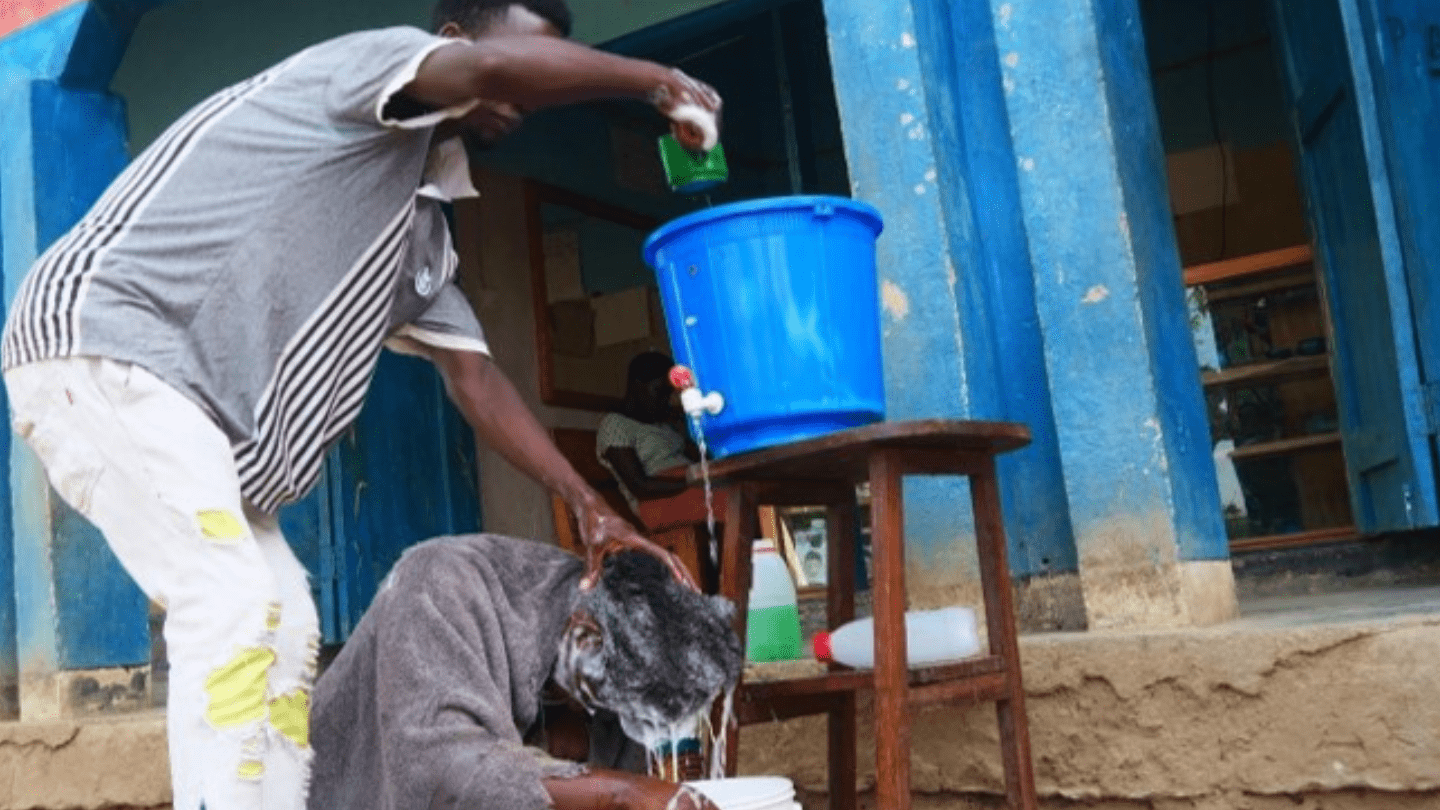 Jacob  washing a customer’s hair at his barbershop. ©UNFPA/Malawi/2024.